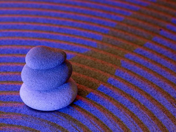 Minimalist zen stones stacked vertically against a dark blue background